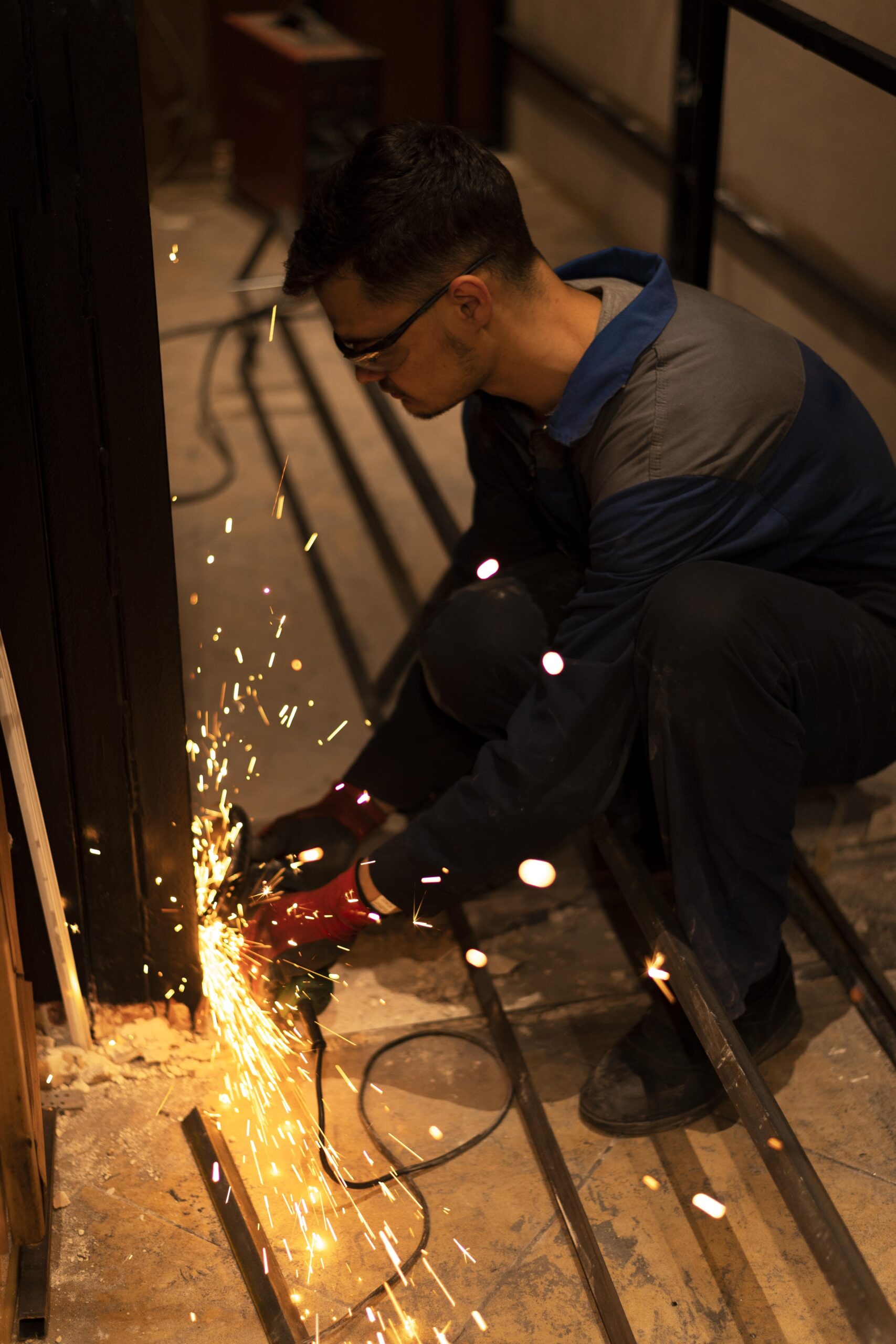 man-using-angle-grinder-with-sparks-min